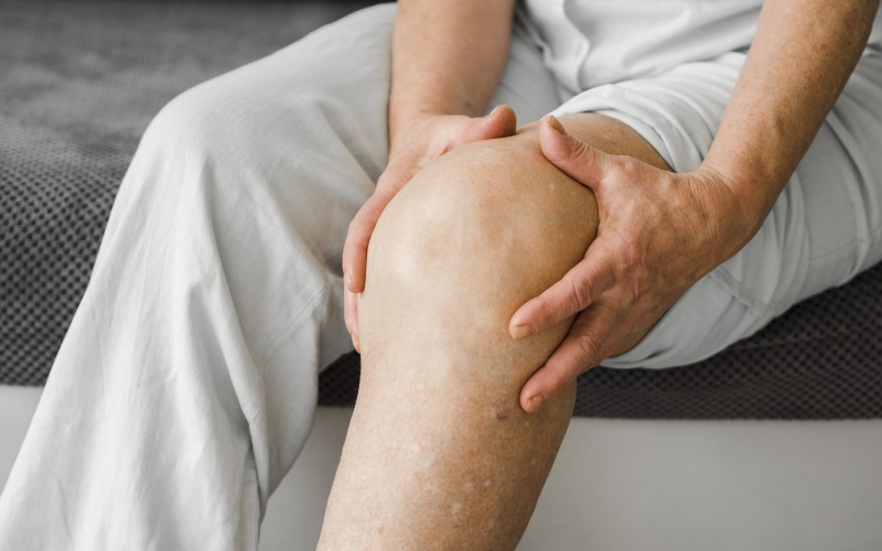 سوزش زانو یک پیرمردی که بر روی تخت نشسته است
